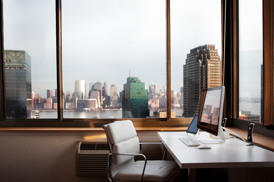 Un bureau aménagé à domicile, avec écran, clavier et grande fenêtre lumineuse