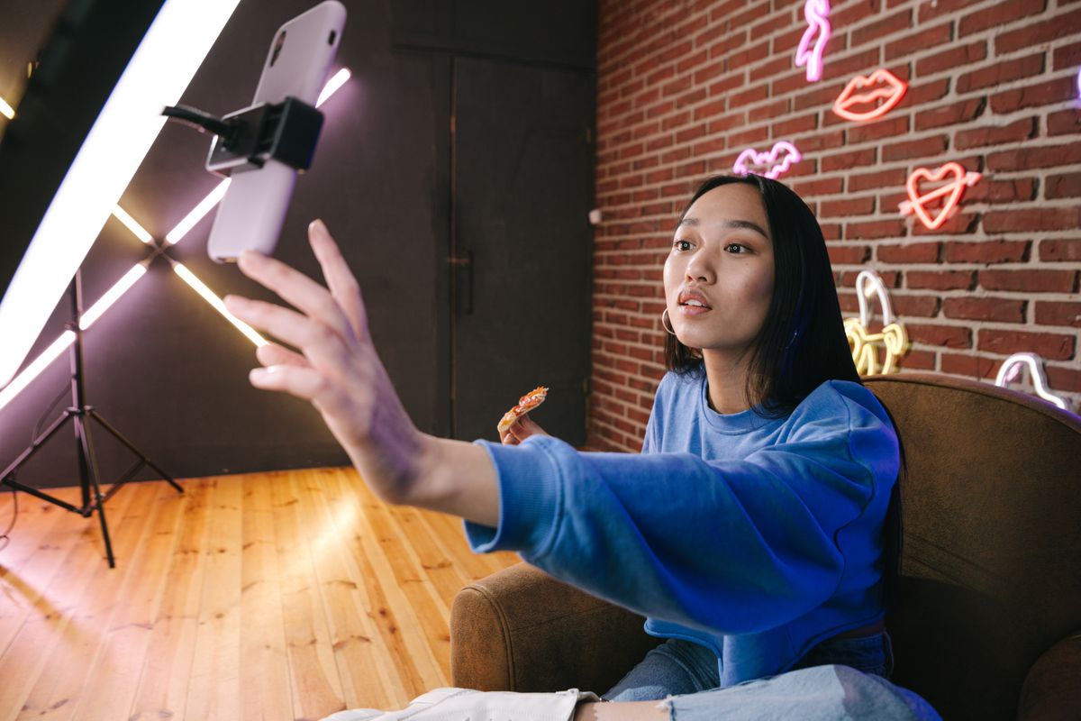 Créatrice de contenu filmant une vidéo avec son téléphone et un éclairage de tournage